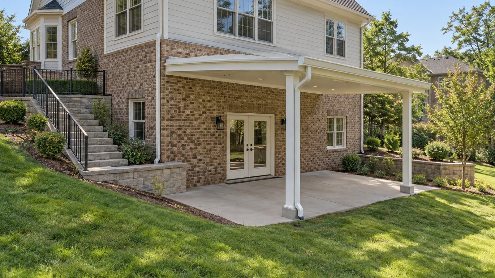 White solid aluminum patio cover outside walkout basement doors with exterior stairs and retaining walls