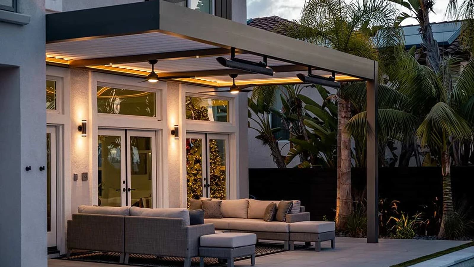 Two fixed radiant patio heaters mounted below an illuminated Azenco R-BLADE louvered pergola