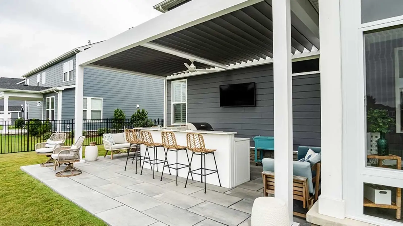 White aluminum louvered pergola installed over a large-format paver patio beside a Charlotte-area style home