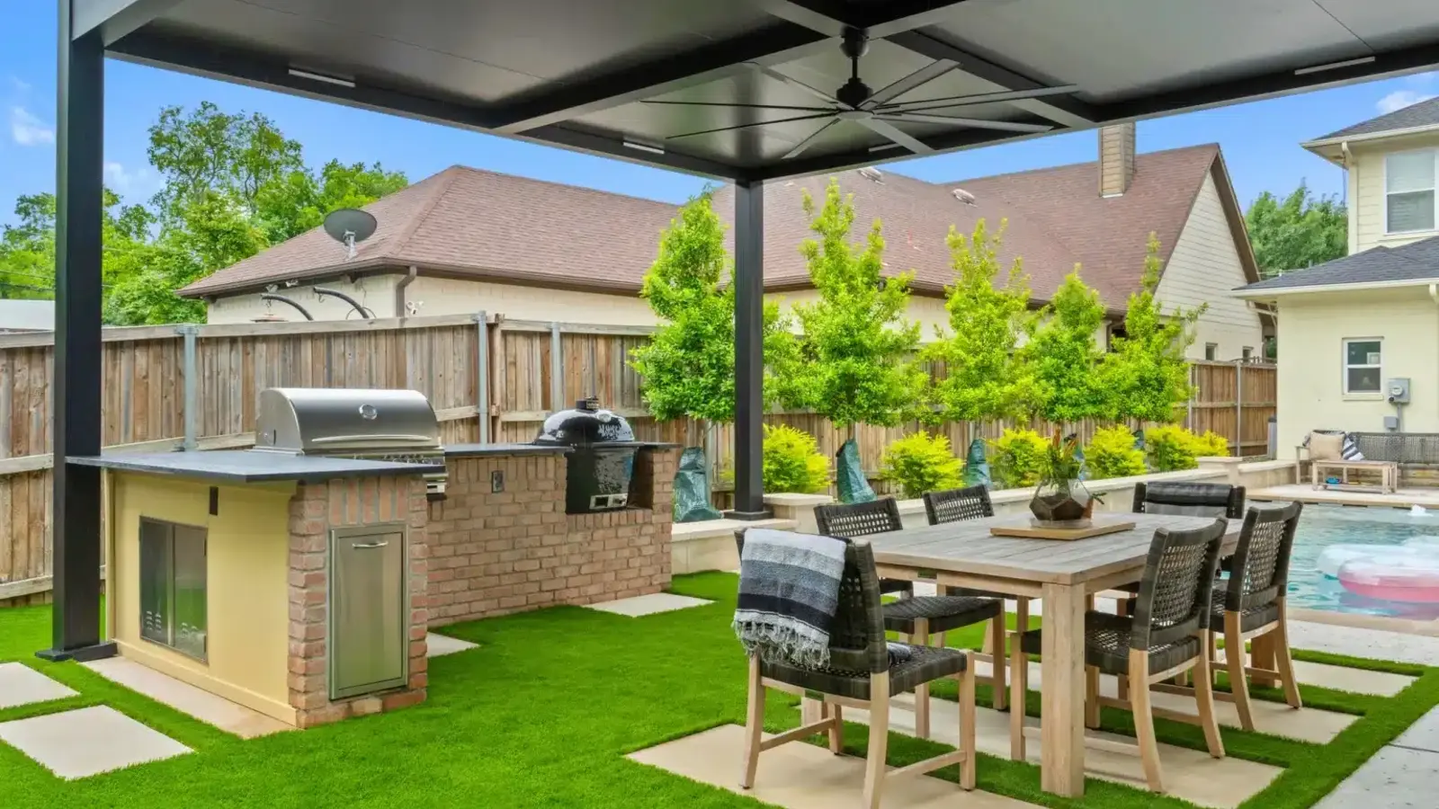Dark aluminum solid-roof patio cover shading an outdoor dining area and kitchen