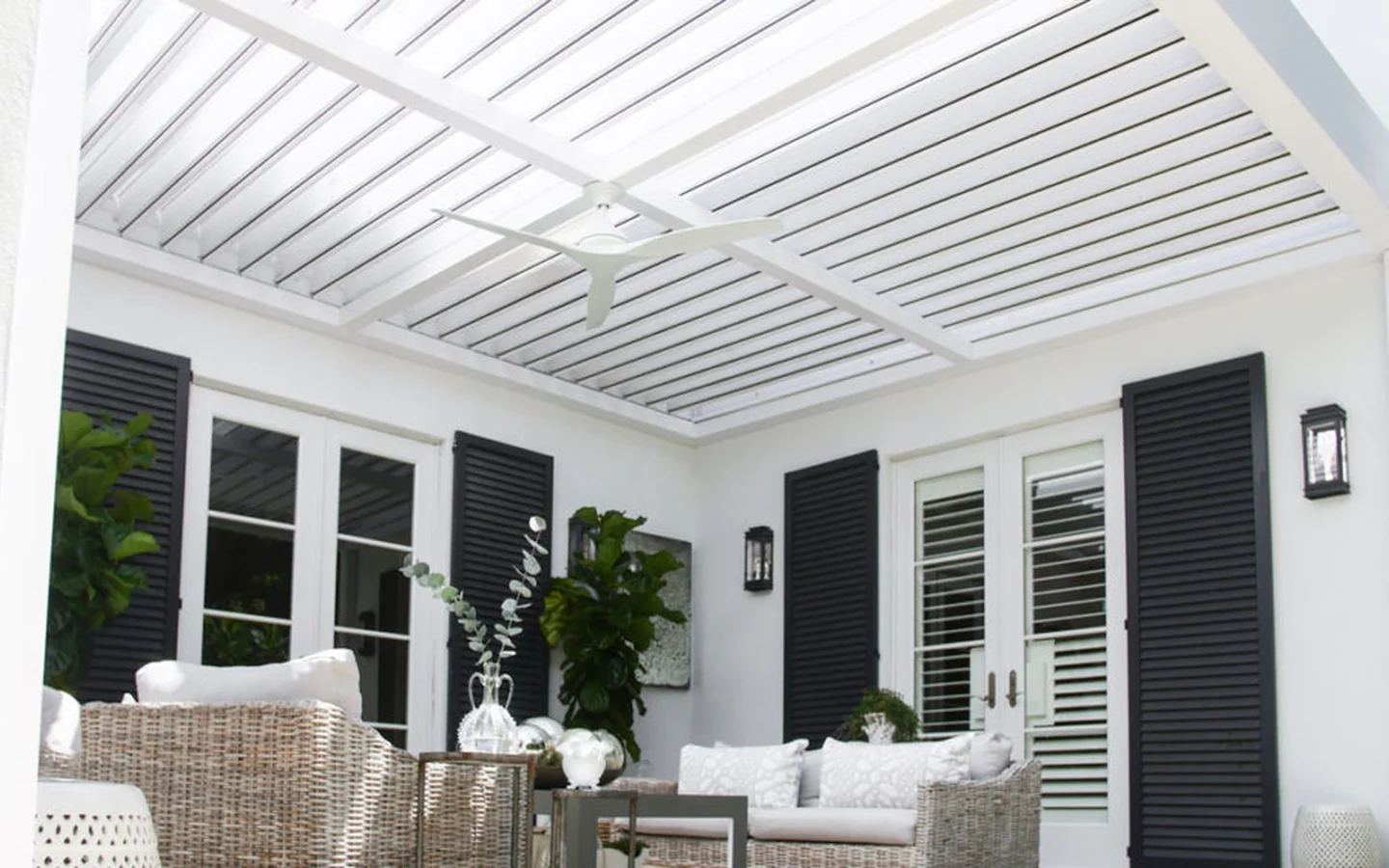 Clean white aluminum louvered pergola covering a furnished patio with open roof blades
