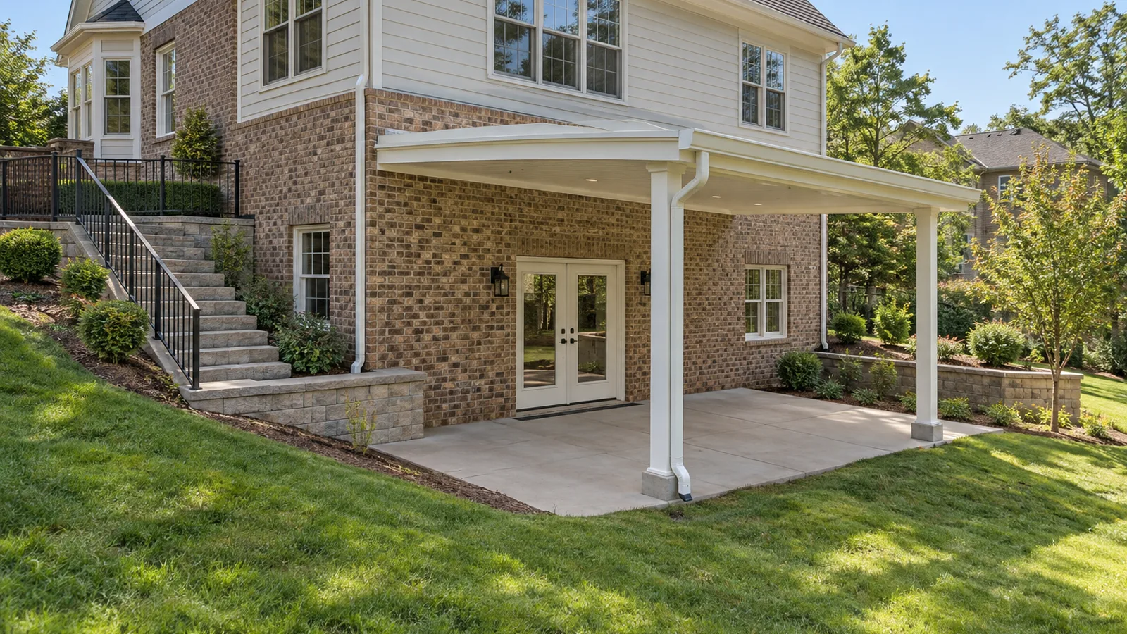White solid aluminum patio cover outside walkout basement doors with exterior stairs and retaining walls