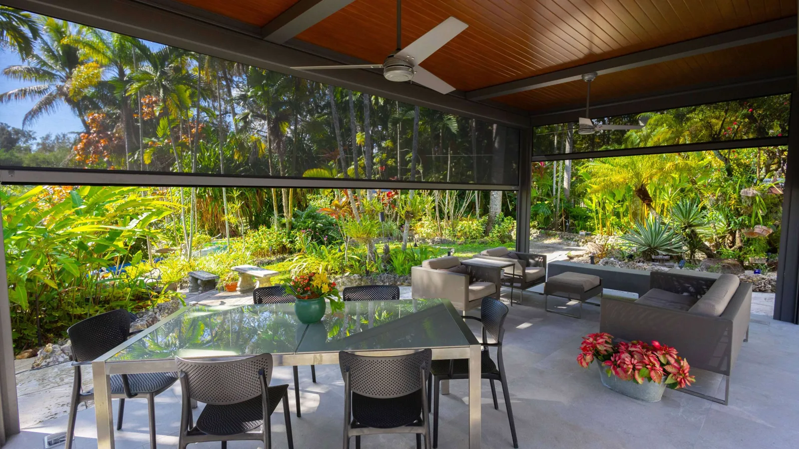 Solid-roof aluminum pergola with dark retractable mesh screens lowered above an outdoor dining and lounge patio
